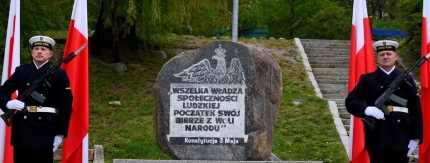 Pomnik Konstytucji 3 Maja z wartą honorową Marynarki Wojennej i flagami Polski